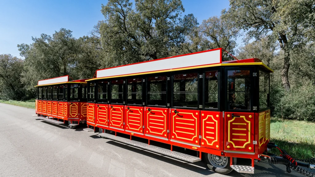 Full Deltrain tourist train with decorated Prime wagons on a scenic tree-lined road