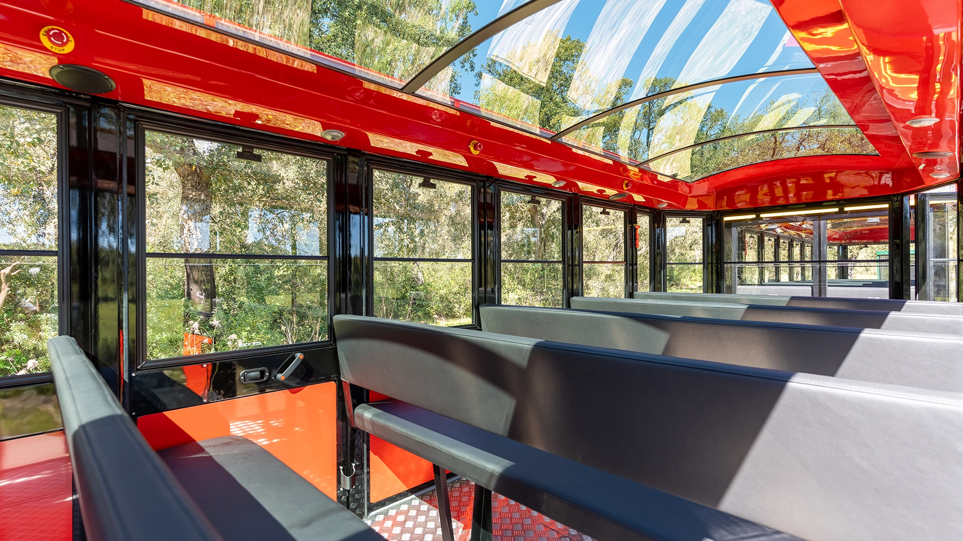 Side bench seating and large sliding windows inside a Deltrain Prime enclosed tourist train wagon